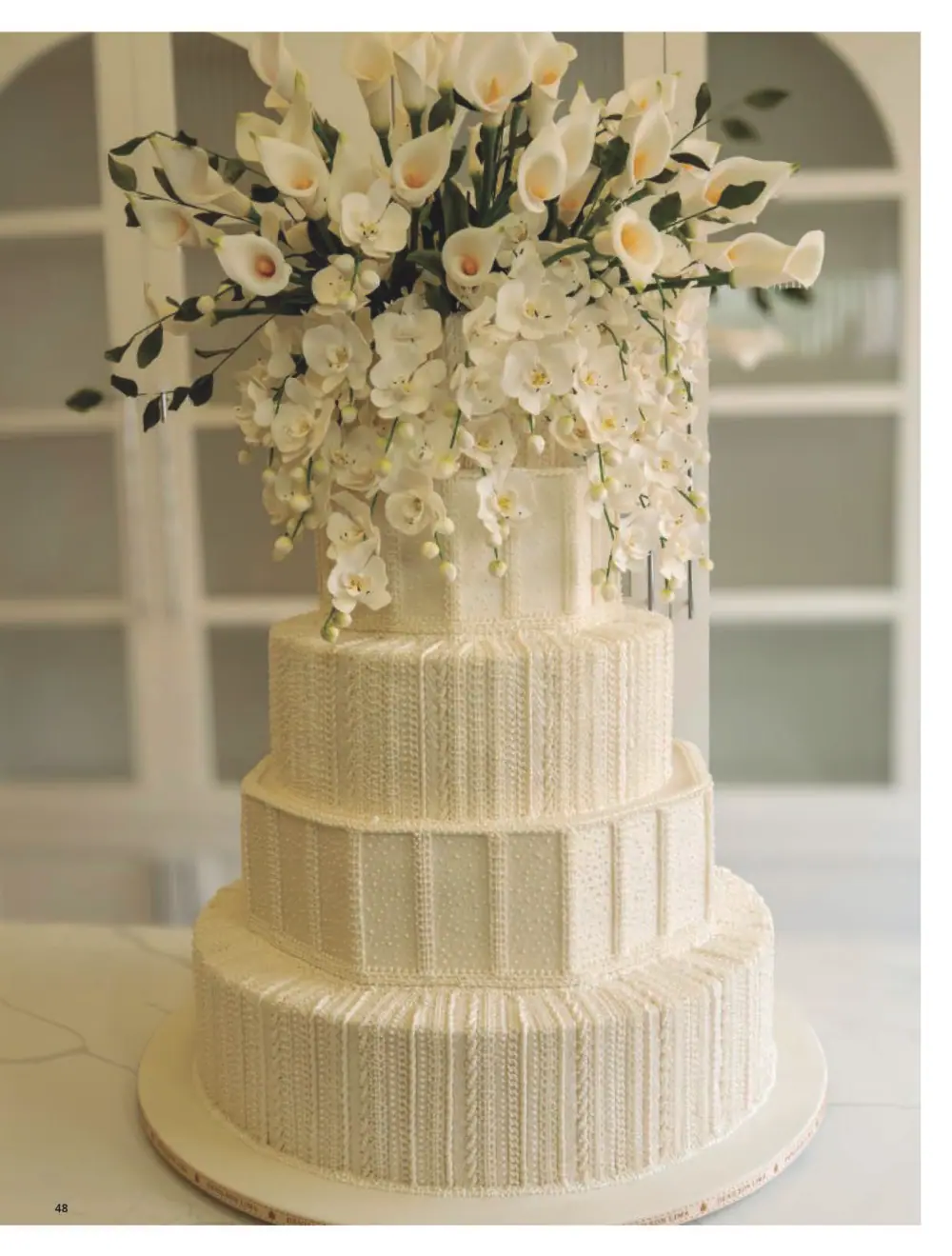 Bolo de casamento branco decorado com copos-de-leite e orquídeas