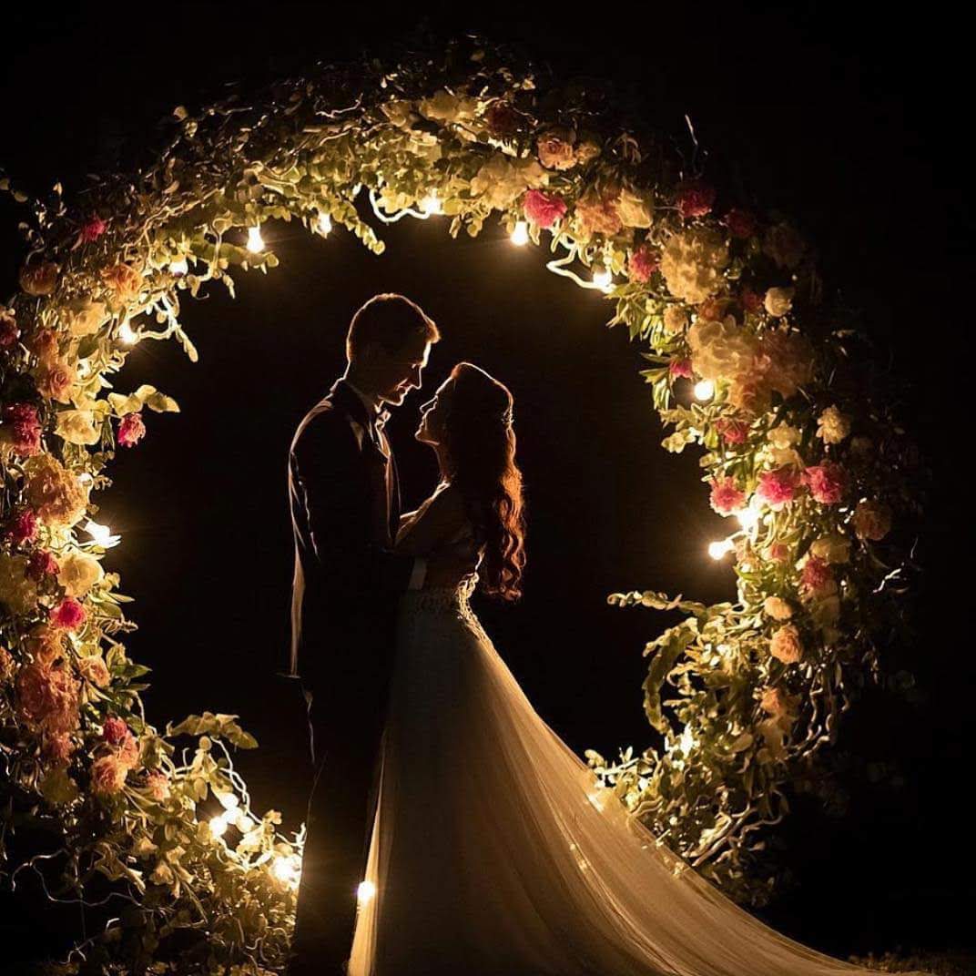 Casal sob o arco iluminado de flores | Foto: acervo local