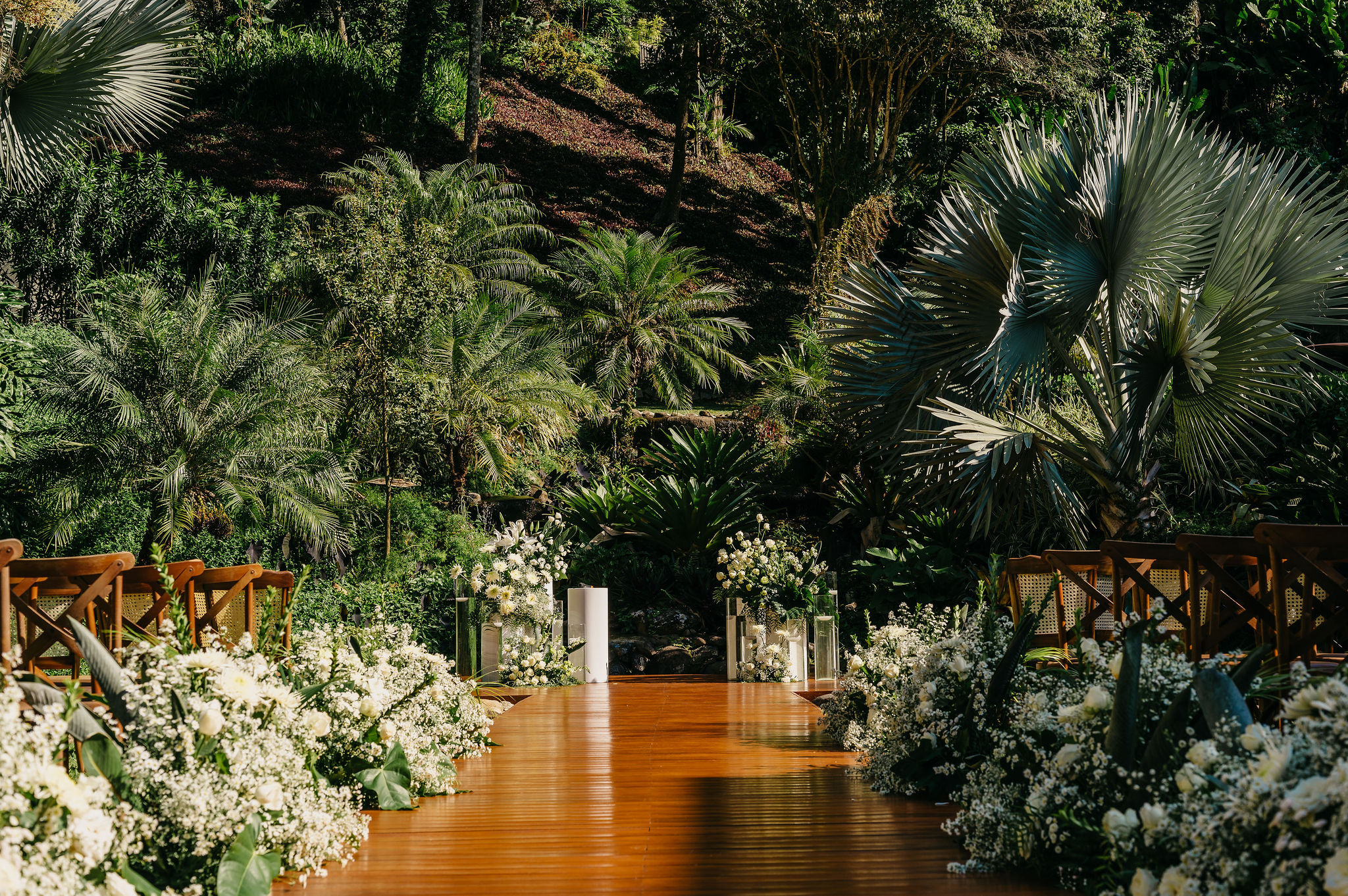 Cerimônia ao ar livre com flores brancas e vegetação tropical ao fundo | Foto: 2Barcos