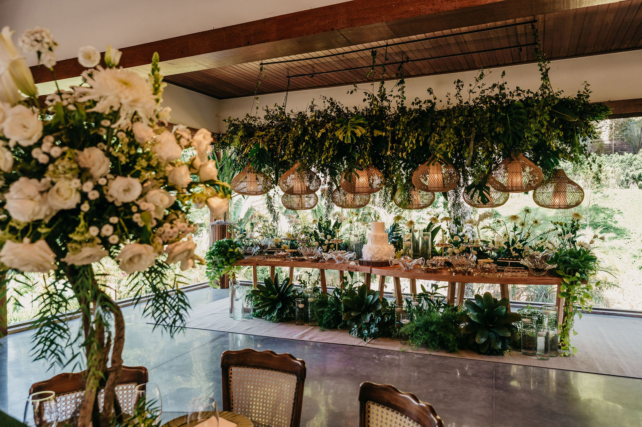 Mesa de doces decorada com flores, folhagens e luminárias de fibras naturais | Foto: 2Barcos