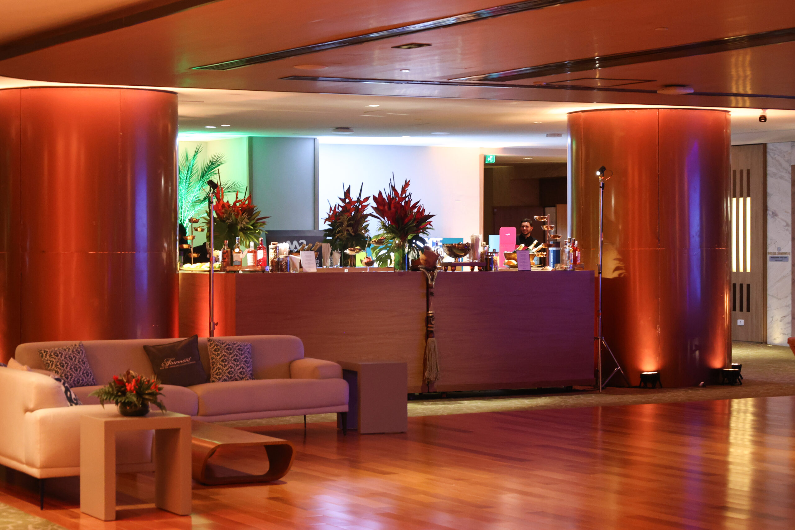 Área de bar do Fairmont Rio apresenta balcão de atendimento, arranjos tropicais e iluminação em tons quentes. | Foto: Divulgação/Fairmont