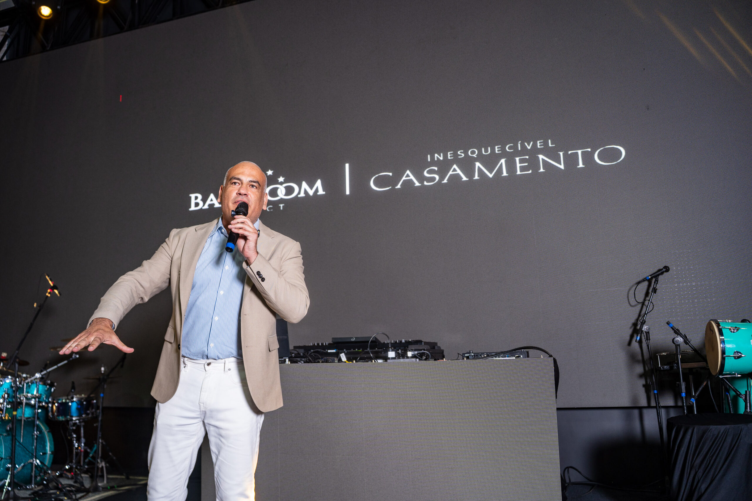Fabiano Niederauer, CEO da Inesquecível Casamento, discursa no palco, diante do painel com as marcas Ballroom e Inesquecível Casamento. | Foto: Chris Machado