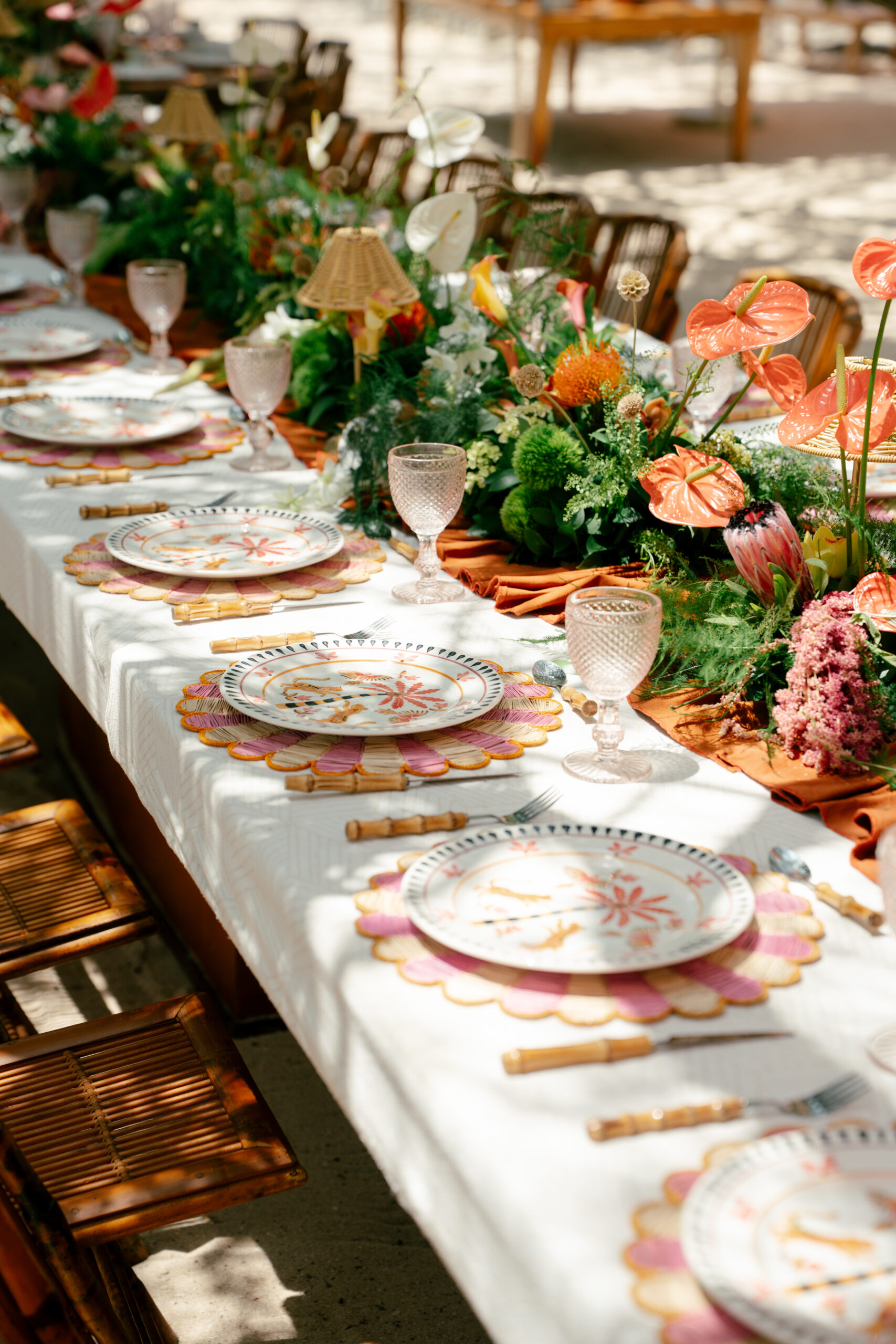 Mesa posta ao ar livre apresenta decoração tropical com antúrios, folhagens, louças estampadas, jogos americanos coloridos e detalhes em fibras naturais | Foto: Compañía Audiovisual
