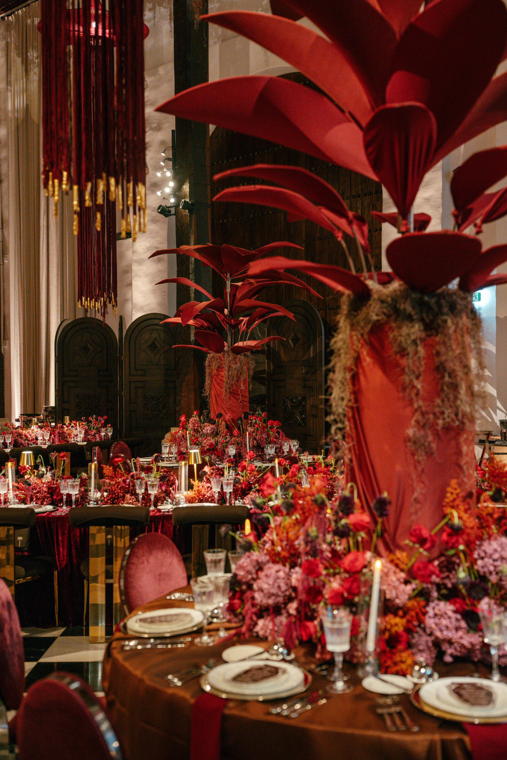 Grandes elementos cenográficos vermelhos, arranjos florais e estruturas suspensas compõem a decoração de um dos ambientes preparados para o Cartagena Wedding Dreams | Foto: Compañía Audiovisual