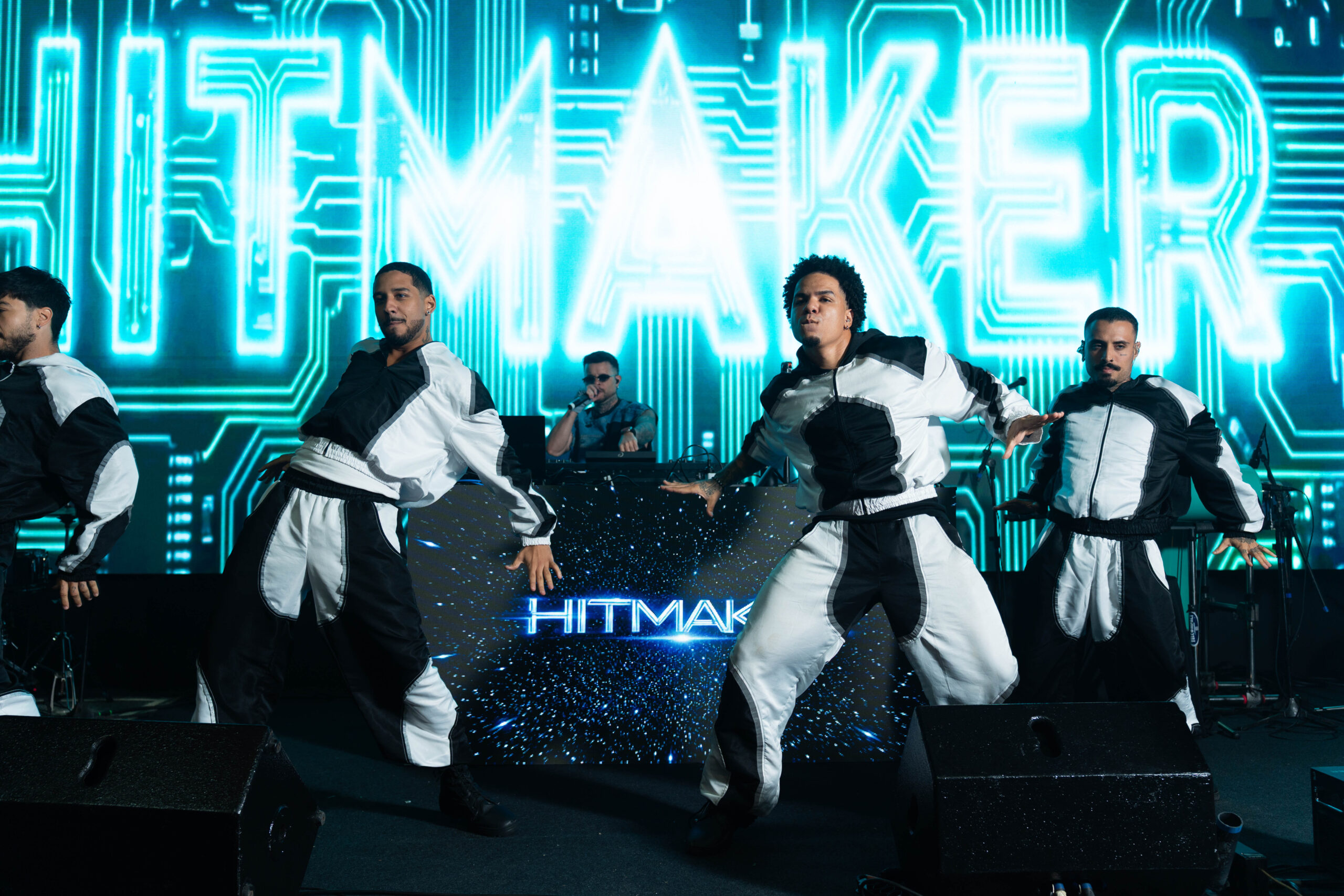 Bailarinos se apresentam durante o show de Hitmaker, com efeitos visuais e iluminação em tons de azul no palco. | Foto: Chris Machado