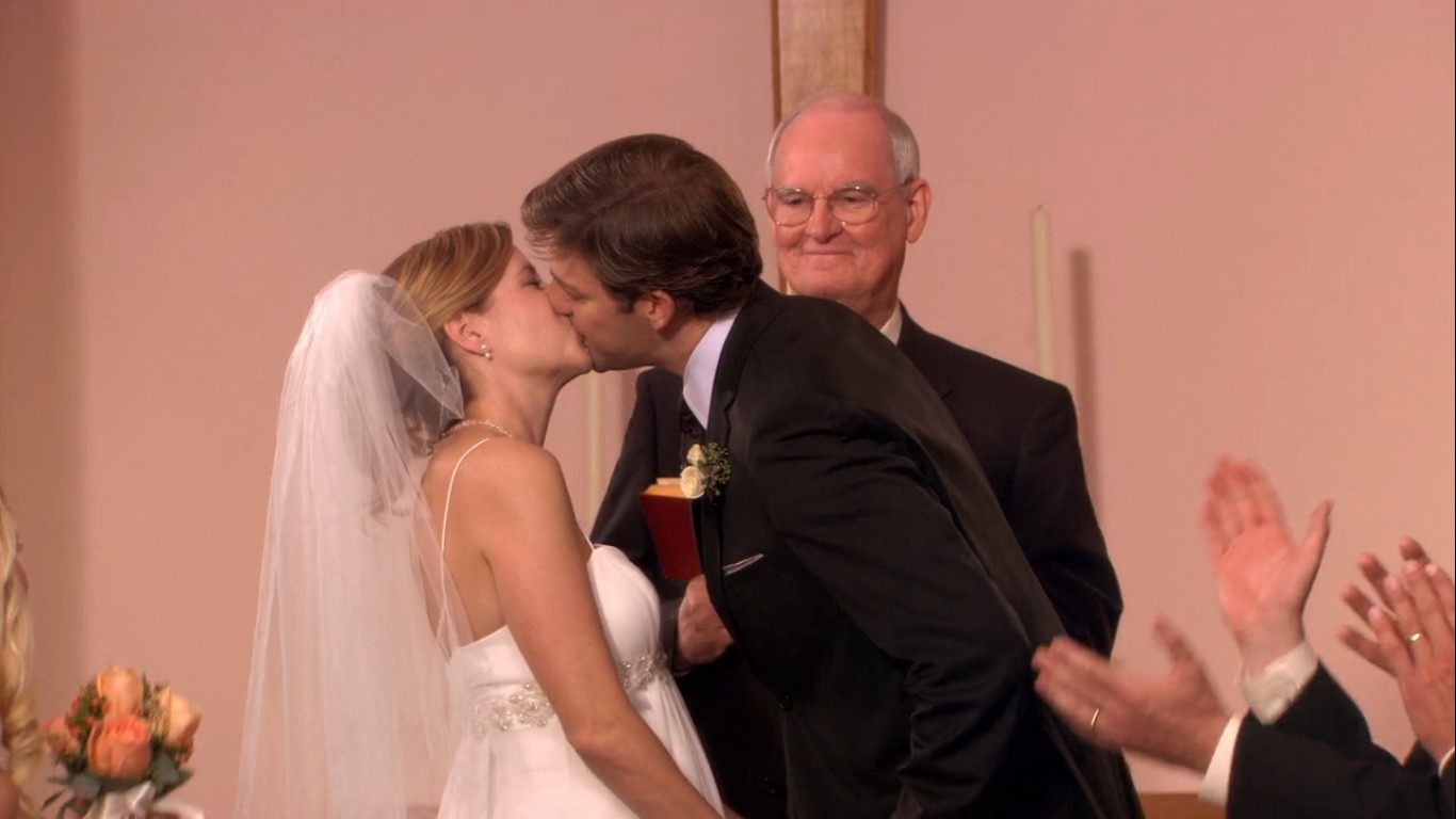 Jim e Pam se beijam durante a cerimônia de casamento na igreja, diante dos familiares, amigos e colegas de trabalho. | Reprodução/Paris Filmes