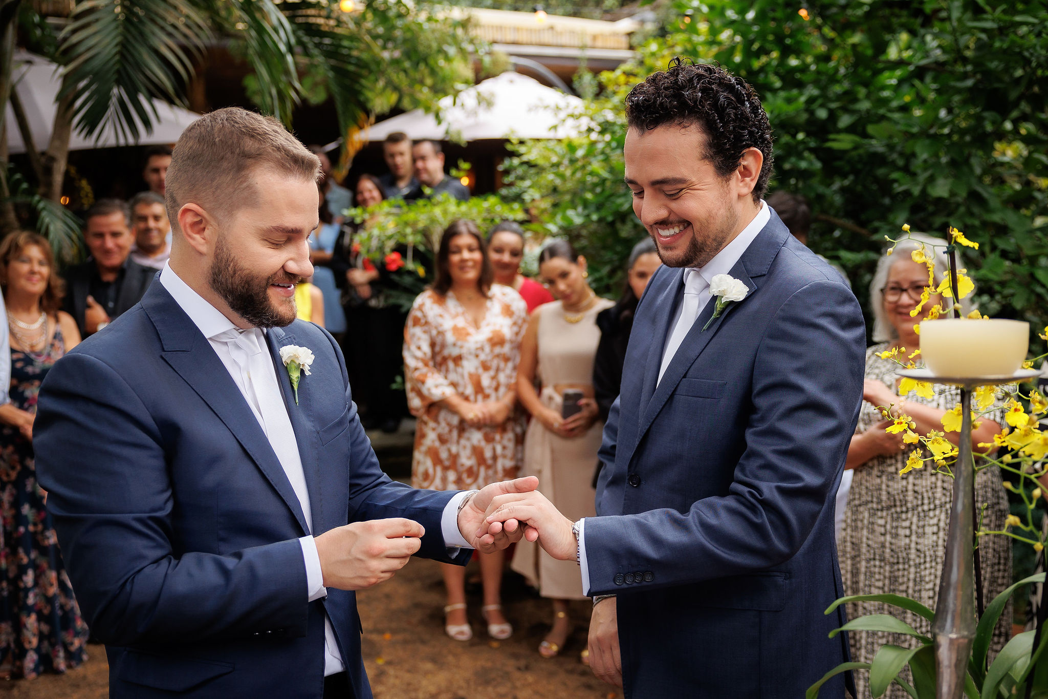 Casal realiza a troca de alianças durante cerimônia de mini wedding, acompanhado de familiares e amigos em um ambiente cercado pela natureza. | Foto: ProPhotos